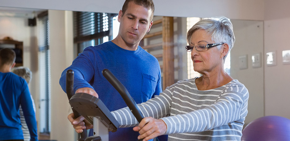 physical therapist with resident on exercise bike
