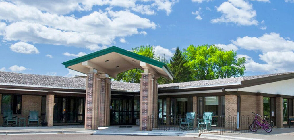 Exterior of Park View Health Care Center in Buffalo, Minnesota, featuring the main entrance with seating and landscaped surroundings.