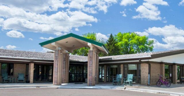 Exterior of Park View Health Care Center in Buffalo, Minnesota, featuring the main entrance with seating and landscaped surroundings.