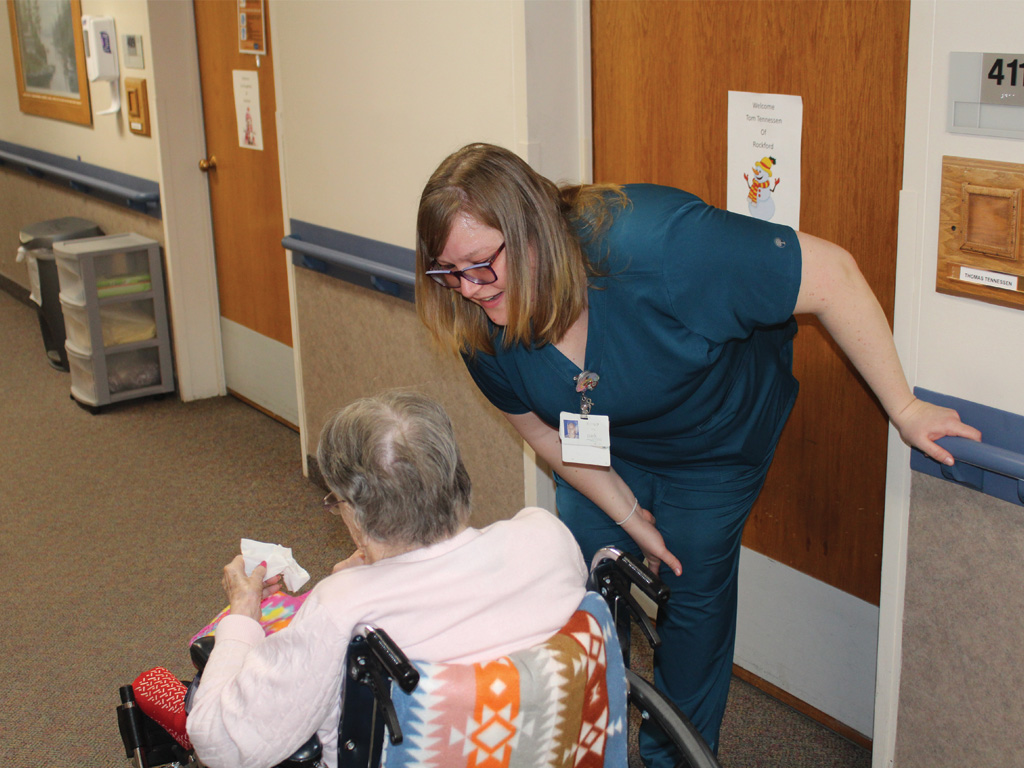 Cassia caregiver supporting an older adult in a wheelchair at a senior living community through the Minnesota Dual Training Grant
